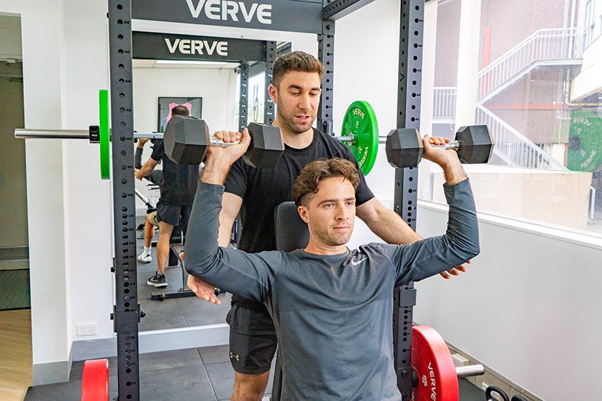 physiotherapist helping client on weight lifting machine