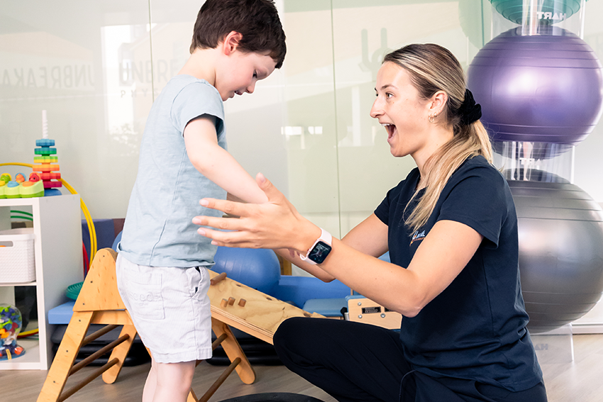 physiotherapist with child on balance ball