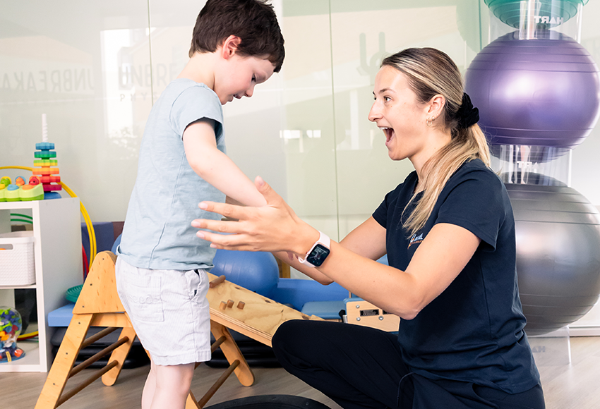 physiotherapist with child on balance ball